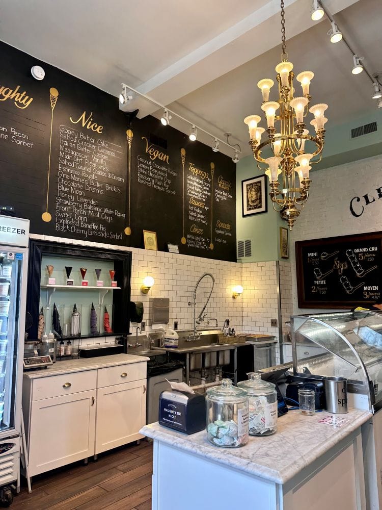 Inside with black menu boards and a chandlier from the ceiling at Clementines, a St. Louis ice cream shop.