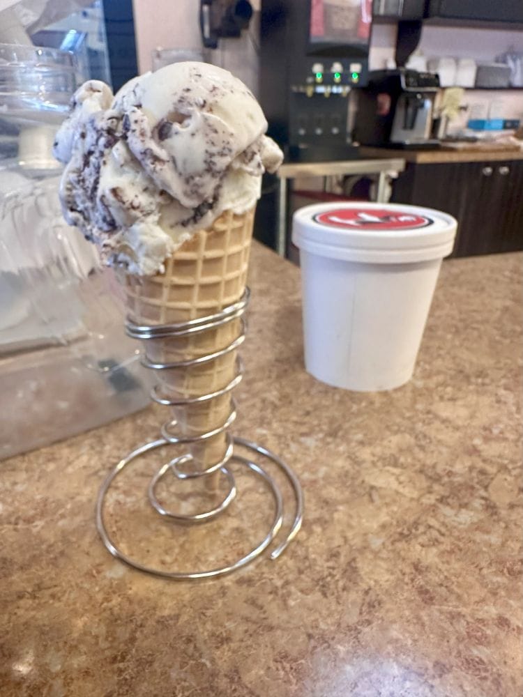 An ice cream cone sitting on a stand on the counter next to a small tube of ice cream in historic Mount Dora.