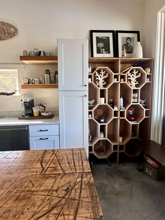 Shelves and cabinets with a wood table in the foreground in the kitchen at a Beaver Lake Arkansas Airbnb.