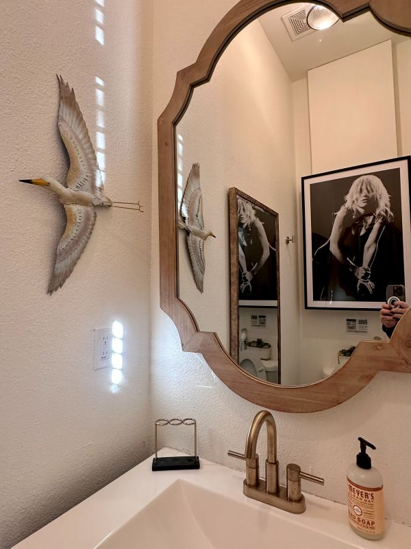 a bathroom mirror with a reflection of the framed photographs on the opposite wall.