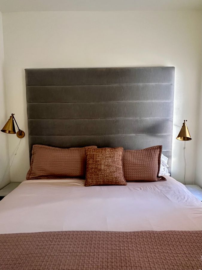 Looking at the king sized bed with large brown tufted headboard and pillows in a Beaver Lake Arkansas Airbnb.