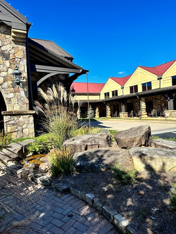 The exterior of Legacy Lodge, red roof, mustard color siding and stone work, a cozy holiday stay.