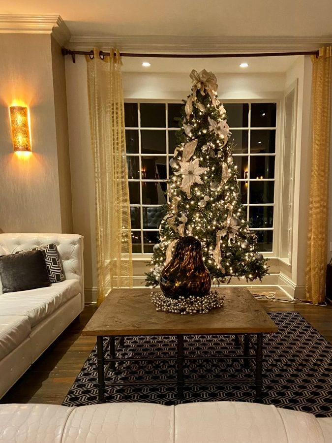 A beautifully elegant lit Christmas tree in front a a window in the lobby of the White house Hotel, a Gulf Coast getaway.