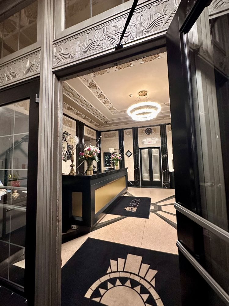 The entrance, looking in from outside through the entry door, at the front desk with the blacks, whites and gold of Art Deco Style, at the Hotel Deco, one of the best hotels in Omaha.