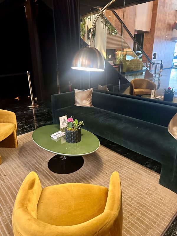Jewel tone velvet chairs and couches, yellows and deep greens, tan floor in the lobby of The Delphi Hotel, a boutique hotel downtown Los Angeles.