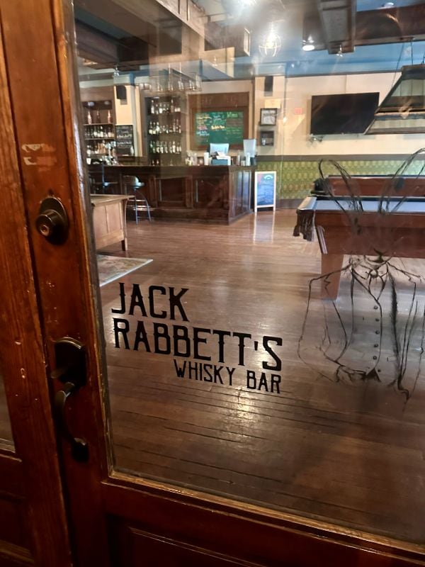 Looking through the window, Jack Rabbett's Whiskey Bar in letters on the window, the bar and pool table beyond, during our weekend in Eureka Springs.