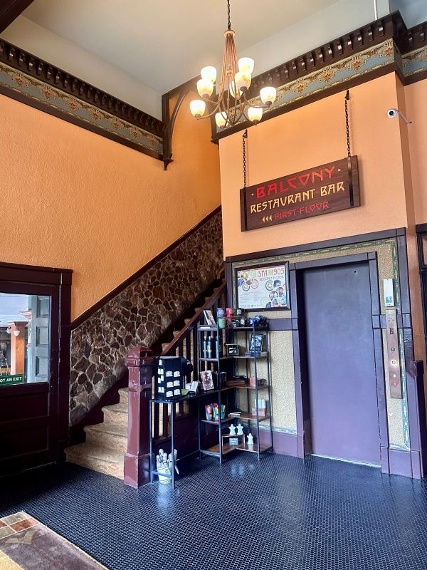 The lobby of The Basin Hotel, orange walls, dark woodwork, and stairs leading upstairs, we stopped on our weekend in Eureka Springs.