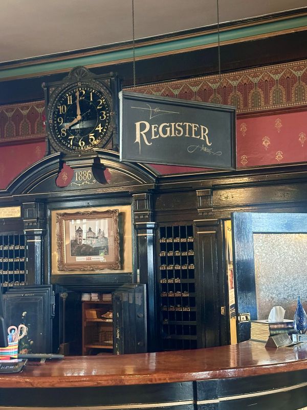 The registration desk with a sign "register" and very antique looking furniture, reds and blacks at the 1886 Crescent Hotel Eureka Springs.