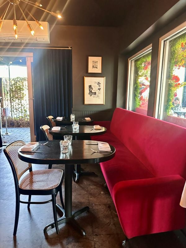 The interior of Petite Chou with a red velvet couch and bistro tables and chairs, a local restaurant for breakfast in Indianapolis.