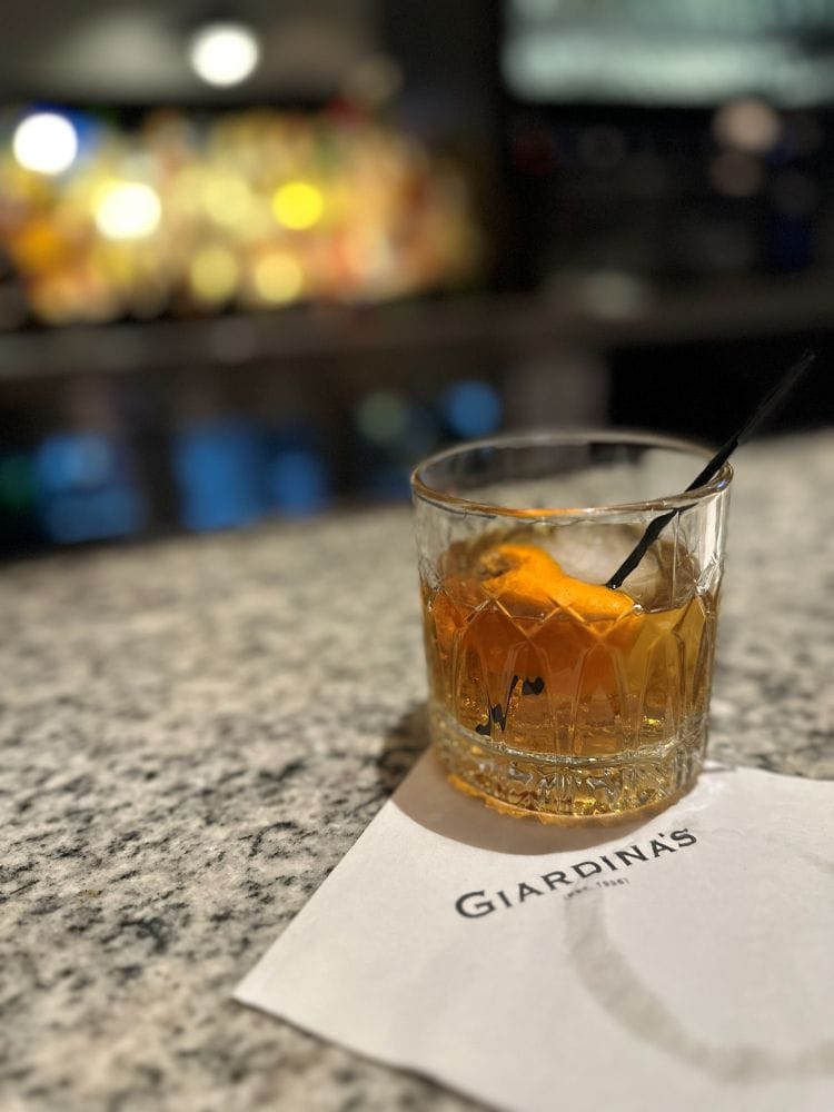 An Old Fashioned on the bar with a napkin with Giardina's on it, at Giardina's at The Alluvian Hotel in Greenwood, MS, during my Mississippi road trip.