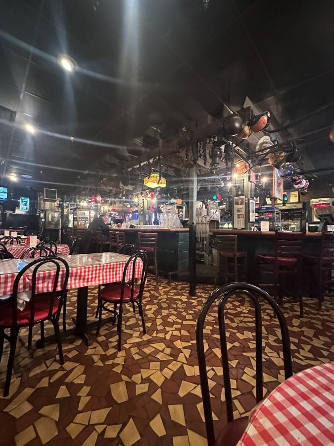 The interior with dark moody vibes , red and white checkered tablecloths and dark wood chairs, at Rendezvous BBQ in Memphis on my Mississippi road trip.