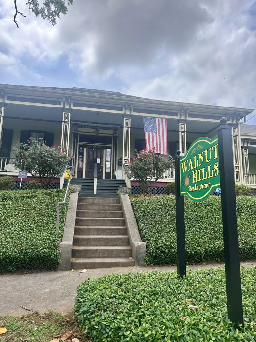 The exterior of Walnut Hills in Vicksburg, a house turned into a restaurant, the full front porch with a sign in front on my Mississippi road trip.