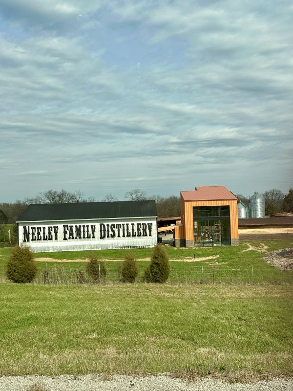 The view of Neeley Family Distillery from the highway, with a large white barn and black letters spelling their name.