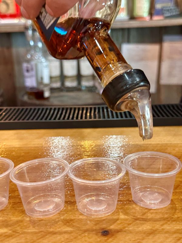 a close up of bourbon being poured in small cups at a tasting at Neeley Bourbon.
