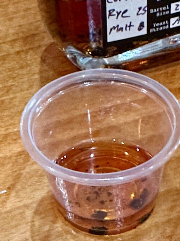 A small cup of bourbon with the black char bits at the bottom at Neeley Bourbon.