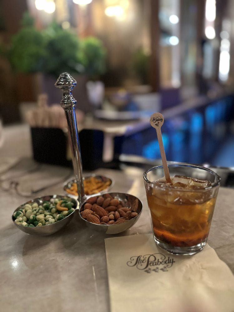 An old fashioneddd on the bar with a caddy of snacks at The Lobby Bar at the Peabody Hotel in Memphis TN.