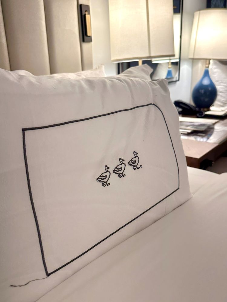 The pillow on the bed in a guest bedroom with three black ducks sewn into the pillowcase at The Peabody Hotel in Memphis TN