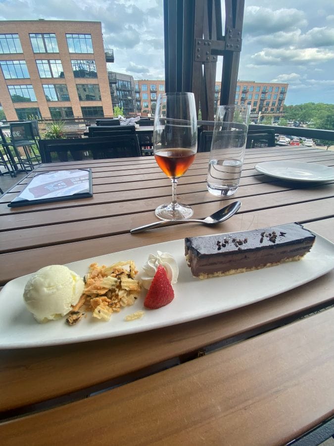 A chocolate dessert with ice cream and port wine with a view of the second-floor patio of Provision, the restaurant at the Ironworks Hotel, an industrial-style hotel in Indianapolis.
