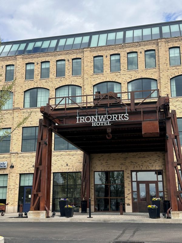 The entrance of the Ironworks Hotel with blonde brick and rust iron facade, an industrial style hotel in Indianapolis.