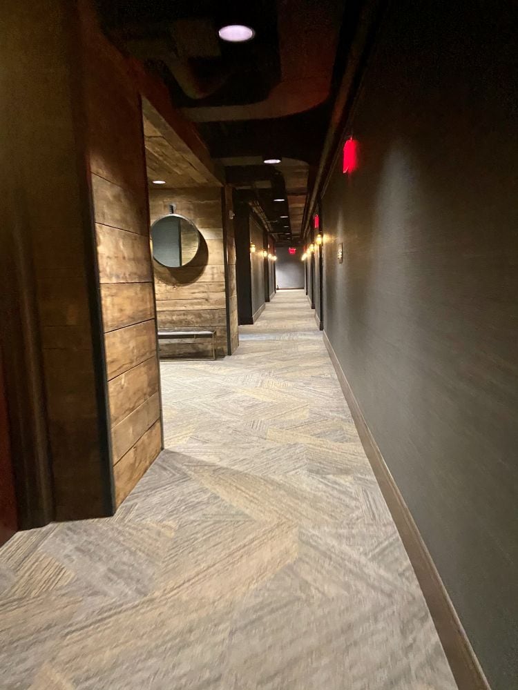 Hallway, gray walls one side, wood plank walls on the other, at the Ironworks Hotel, an industrial style hotel in Indianapolis.
