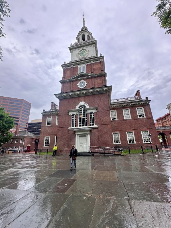 A cloudy day and Independence Hall with slick sidewalks from rain.