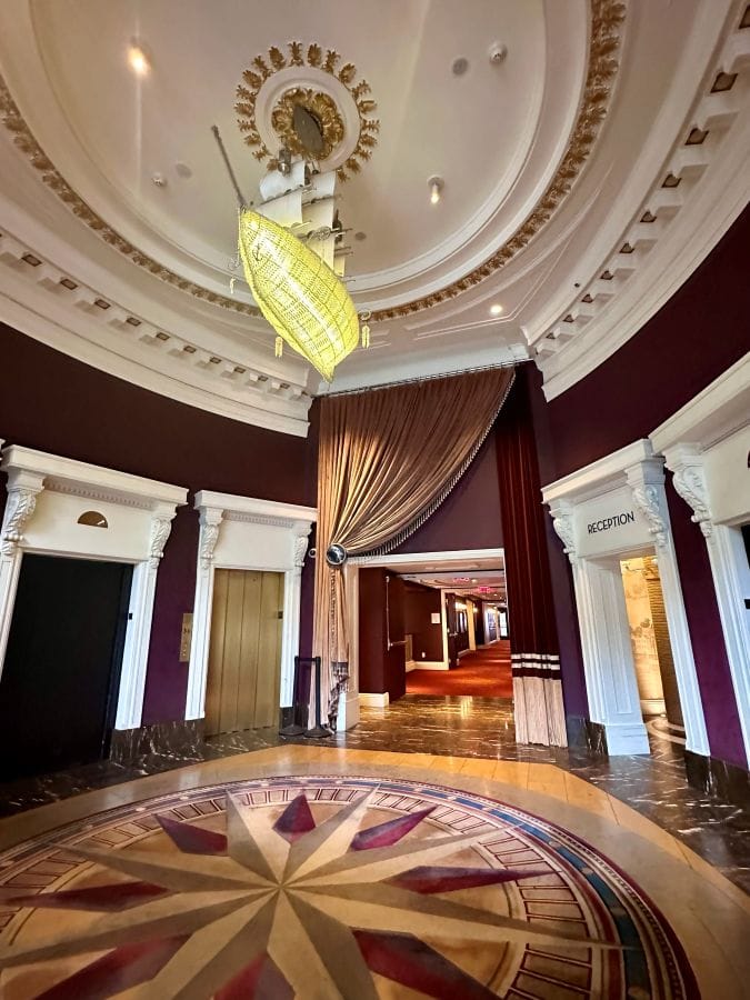 The circular lobby entrance with burgandy wall. tiled floor and a sail ship chandelier hanging from the ceiling at Kimpton Hotel Monaco.