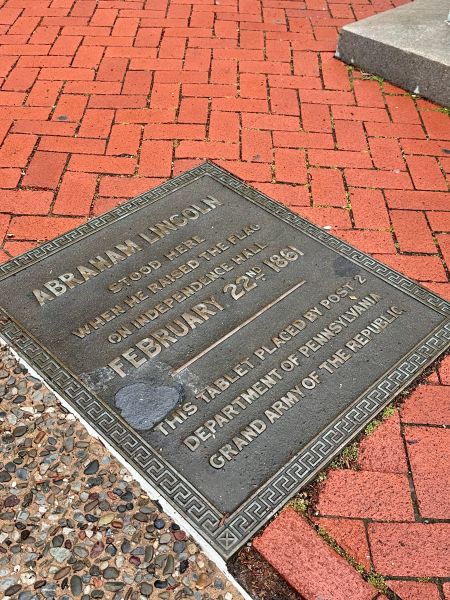 A bronze marker in the brick indicating where Abraham Lincoln stood to raise the flag in honor of George Washington in 1861.