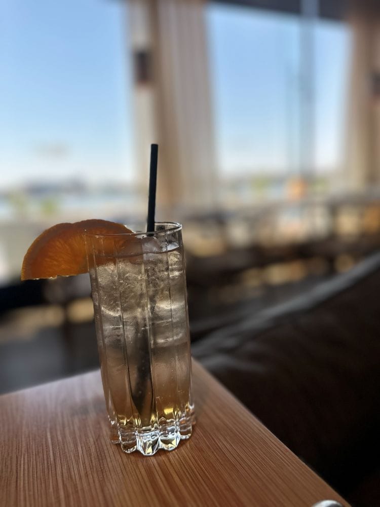 An icy cocktail on the table with a harbor view in background at La Jette, one of the best breakfast spots in baltimore