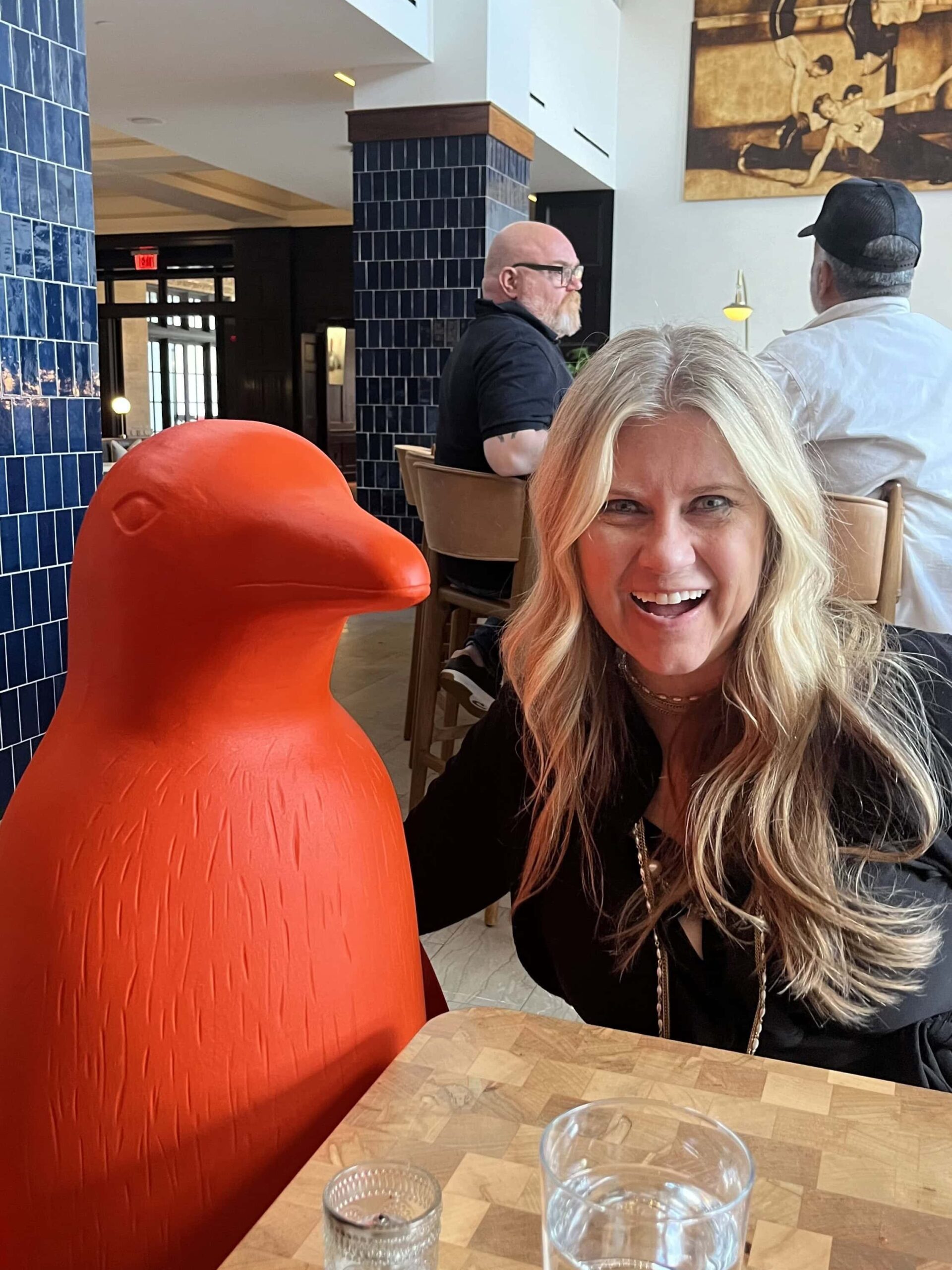 Bev Laughing with a 4ft tall 21c Hotel Orange Pengiun standing next to her.