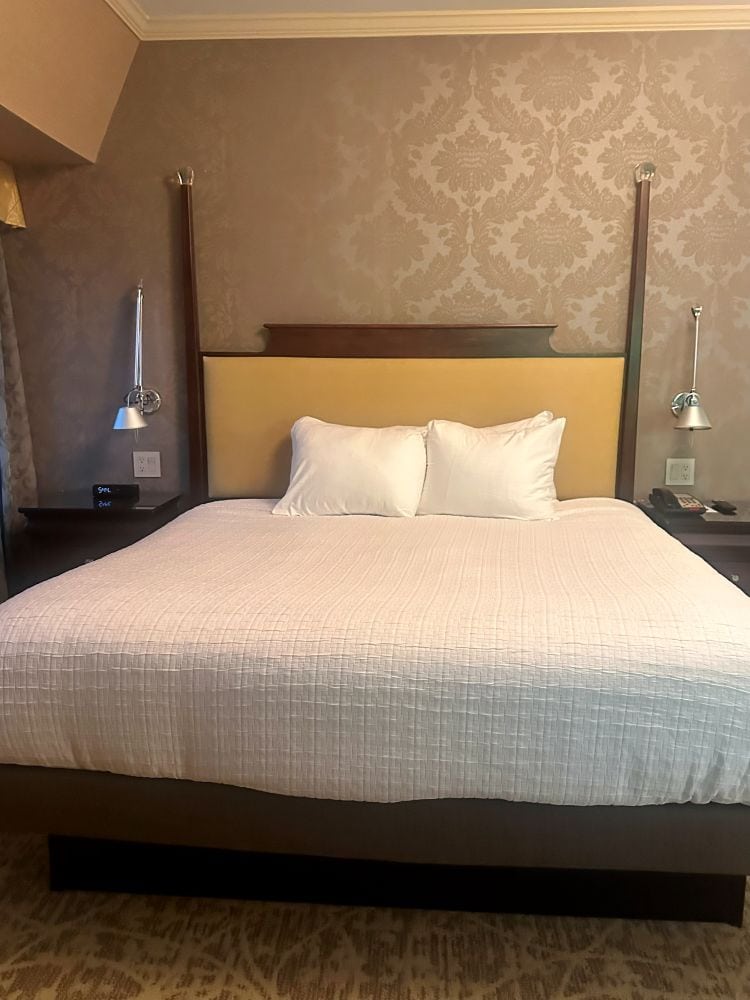 The four poster bed with period wallpaper and white bedpsread at the Chestnut Hill Hotel Philadelphia.