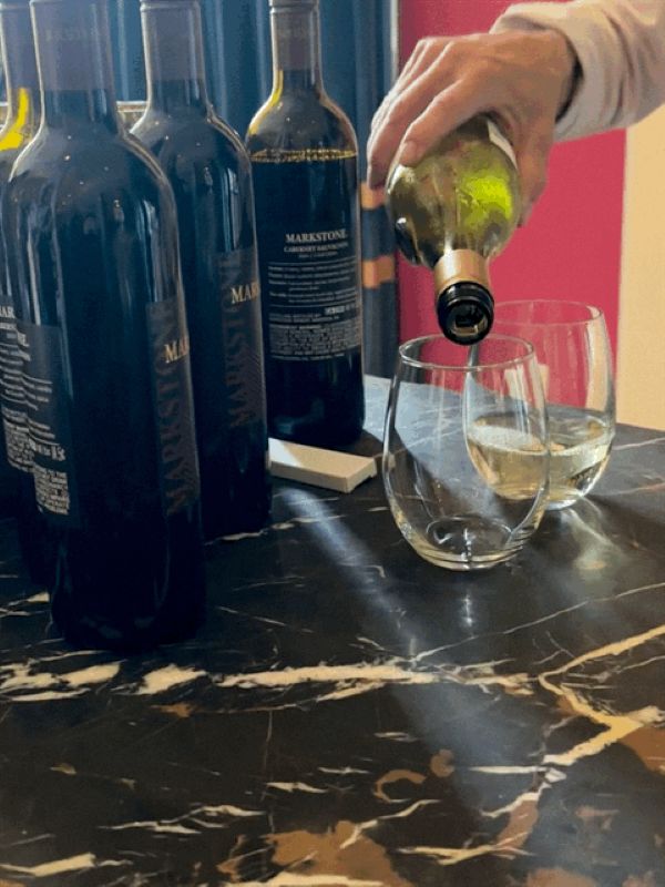 Pouring white wine in a glass at the wine happy hour at Kimpton Monaco, a hotel near Independence Hall.