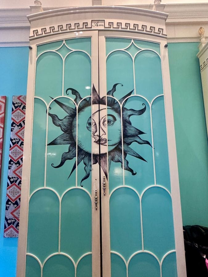 A teal and white wardrobe in the lobby with an animated sun painted in the front at the Kimpton Monaco, a hotel near Independence Hall.