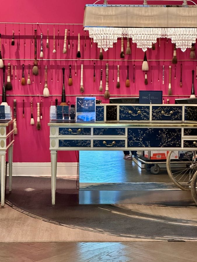 The pink wall with Asian brushes hanging on it behind the guest desk at the Kimpton Monaco, a hotel near independence Hall.