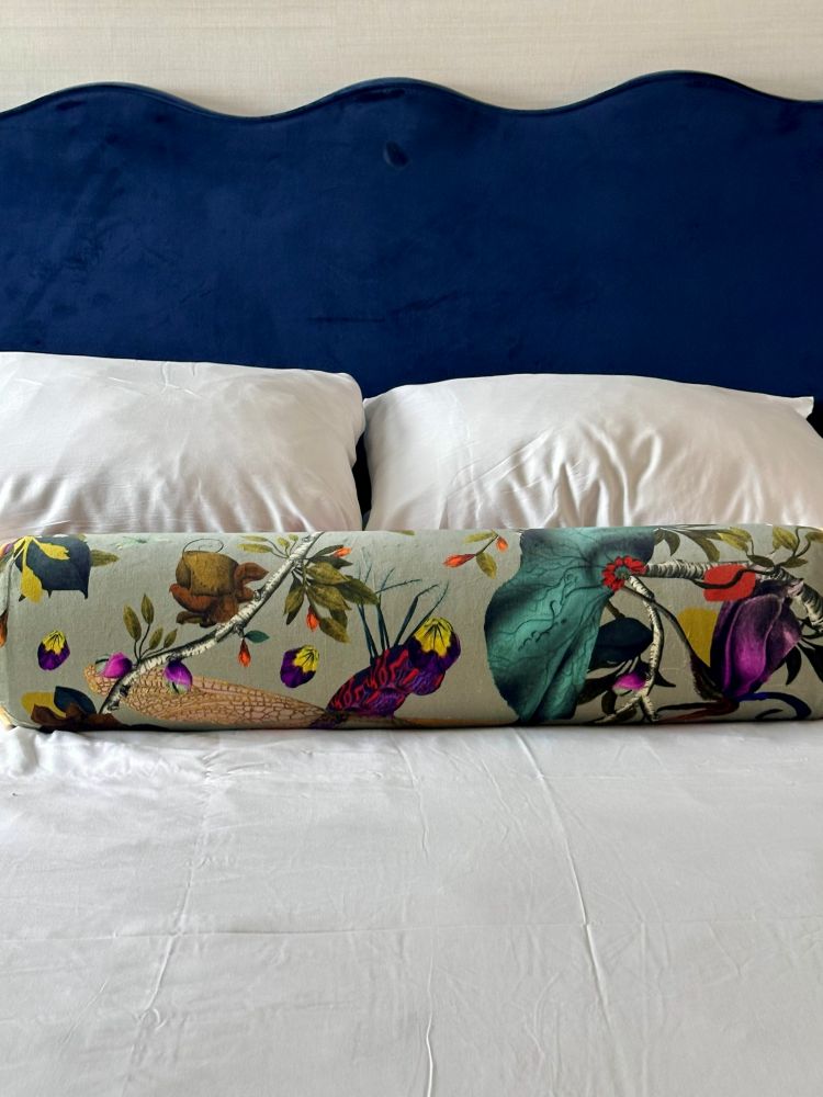 a close up of white pillows, a lower circle pillow and a blue velvet headboard on a bed in a guest room at the Kimpton Monaco, a hotel near Independence Hall.