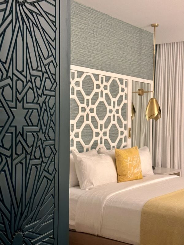 A guest room with a carved green door and a white and yellow bed in the Alfond Inn in Winter Park Florida.