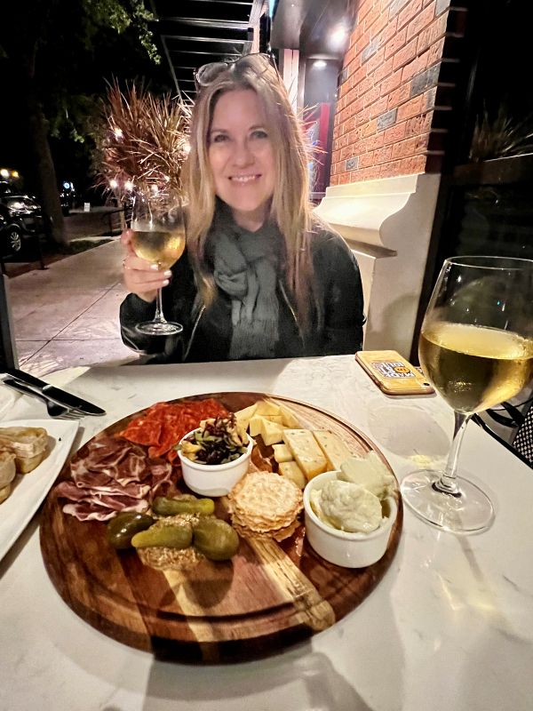 Bev with a glass of wine and cheese and meats on a plate in front of her in Winter Park Florida.