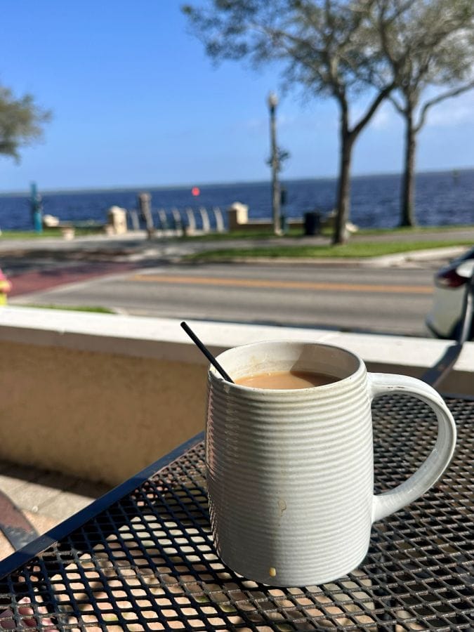A mug of coffee on an outdoor table in the foreground with the Lake in the background in Sanford Florida.