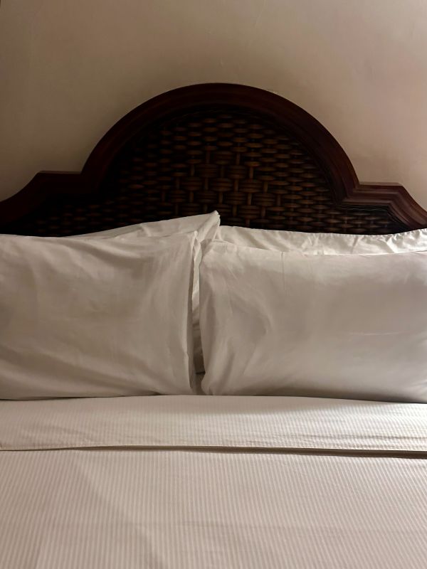 A bed with a curved wooden antique headboard and pillows at the Park Plaza Hotel, a Winter Park Floriday Hotel.