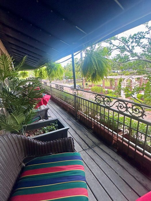 the balcony with the brown whicker chairs, and tables, ferns hanging, and Central Park in the background, at the Park Plaza Hotel, a Winter Park Floriday Hotel