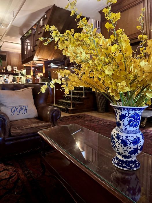 The lobby with a large display of yellow flowers on a wooder coffee table and the welcome desk in the background at the Park Plaza Hotel, a Winter Park Florida Hotel.