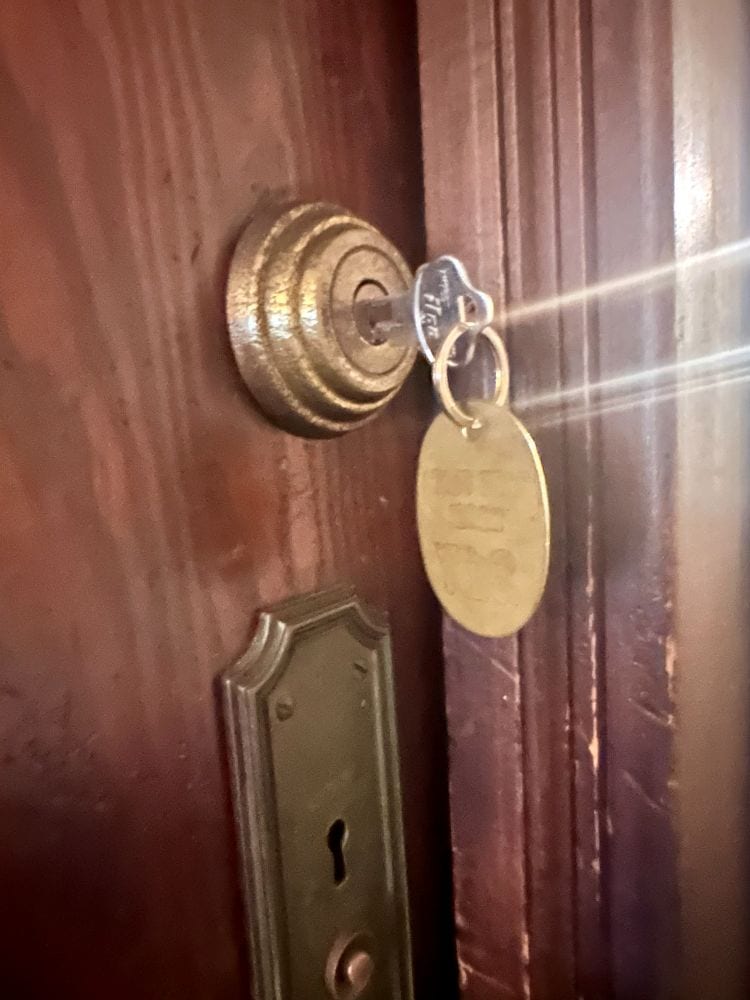 A brass key chain and key in a bolt lock in a guest room door at the Park Plaza Hotel, a Winter Park Florida hotel.