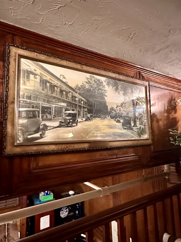 A large historic black and white photograph of the hotel hanging on a wood panel wall above the staircase at the Park Plaza Hotel, a Winter Park Florida hotel.