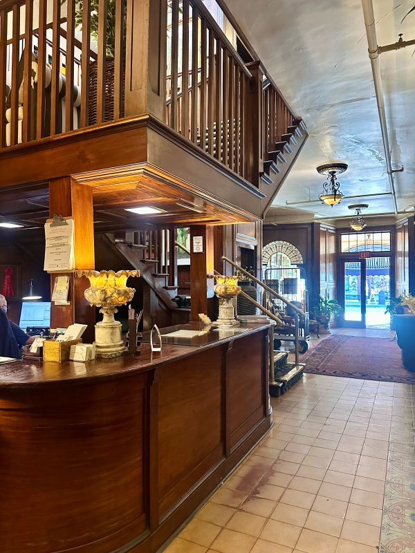 The lobby with the wood welcome desk and staircase, looking to the entry doors in the background at the Park Plaza Hotel, a Winter Park Florida Hotel.