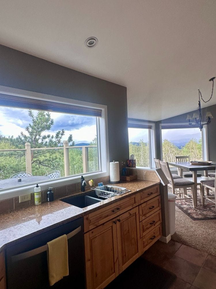A view from the kitchen to the dining room with all the windows looking out at the mountain range in Alpina Haus.