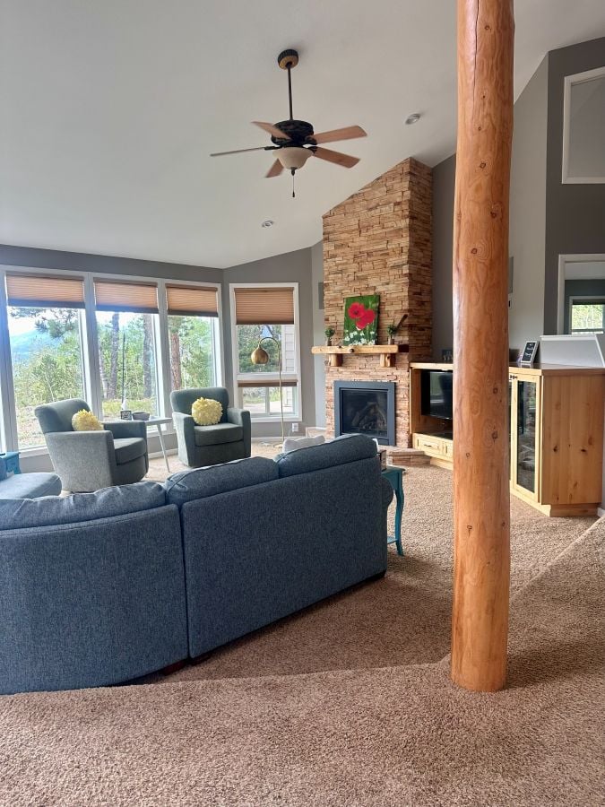 The living room with a fireplace, couch and large windows at Alpina Haus on our Colorado mountain retreat.
