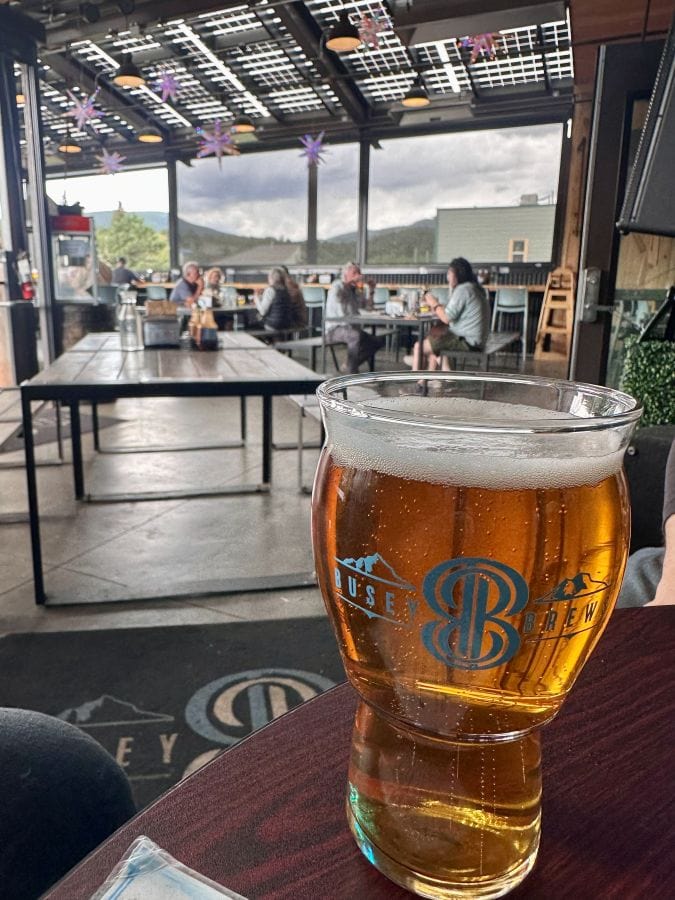 A beer on the table and the patio in the background at Busey Brews in Nederaland during our Colorado Mountain Retreat.