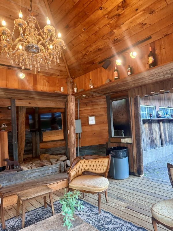The outdoor covered lounge at the pavilion with rustic wood walls and chandeliers at the Brown Mountain Beach Resort.