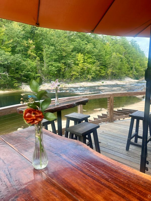 A table on the deck at the pavilion with th ebeach and creek in the background at the Brown Mountain Beach Resrt.