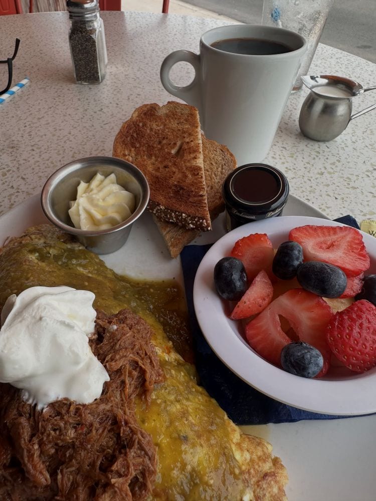 Breakfast with toast, fruit, and coffee on a table at The Morning Squeeza in Scottsdale, Arizona.