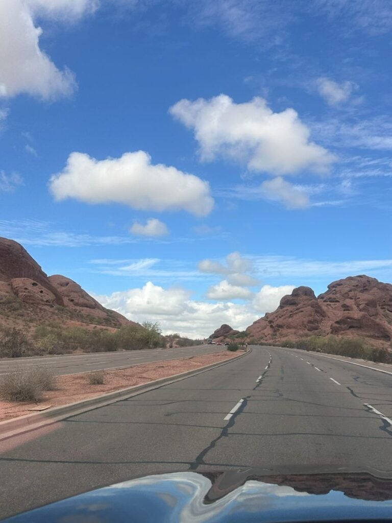 Open desert highway with red rock formations and blue sky in Scottsdale, Arizona.